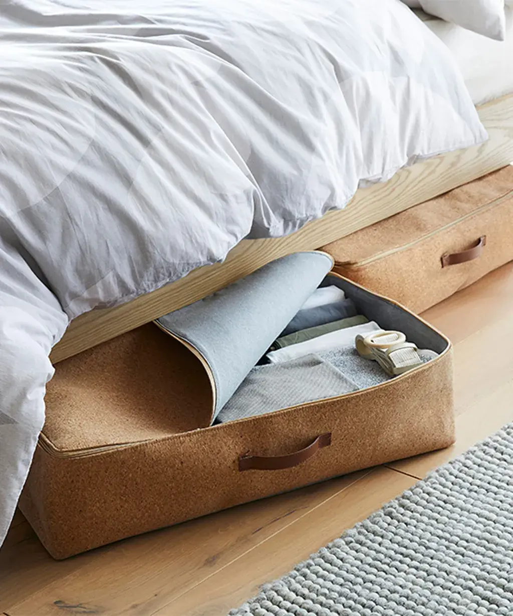 Organized under bed storage containers in a small bedroom with clear labeled bins