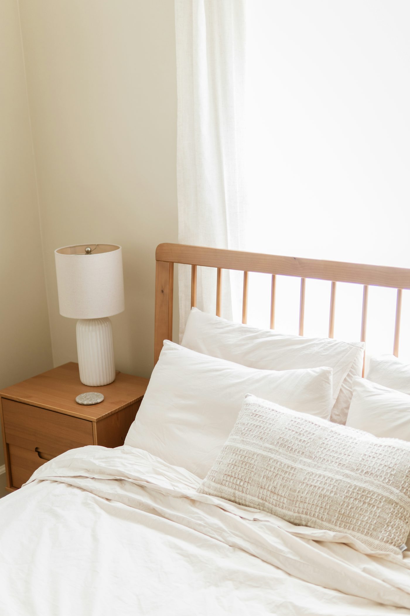 Small apartment bedroom styled with warm neutral bedding soft lighting and intentional decor