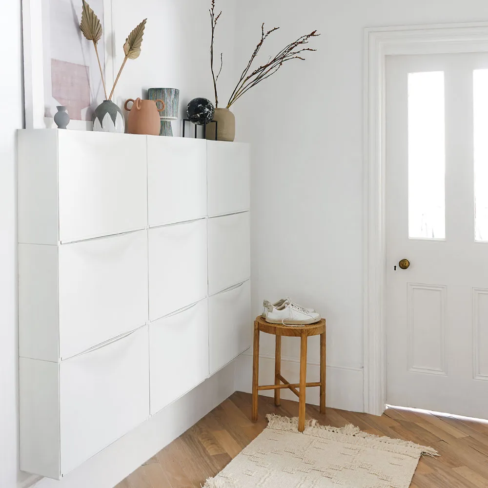 Slim shoe cabinet in a small hallway with styled decor on top