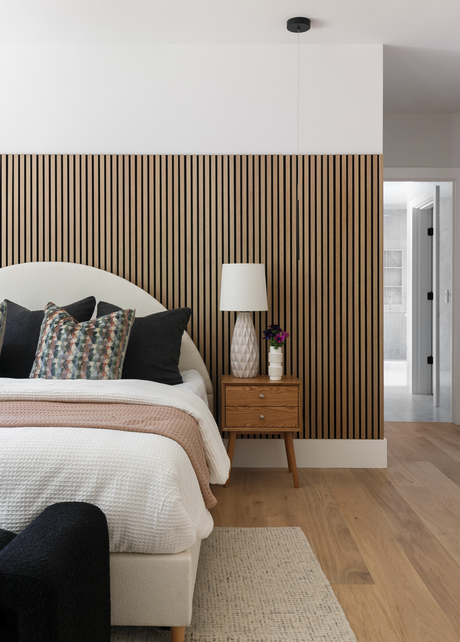 Bedroom with wood slat accent wall behind the bed creating architectural depth