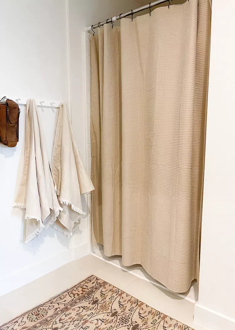 Rental bathroom with textured linen shower curtain in warm neutral tones