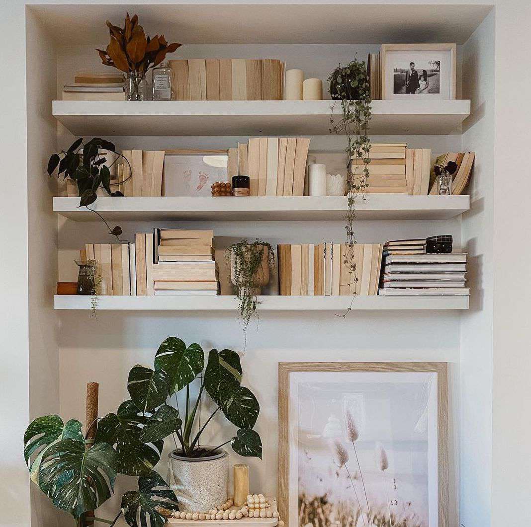 Floating shelves styled with plants candles and books in a neutral apartment