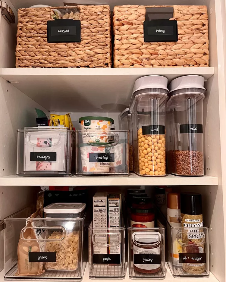Clear storage bins in an organized pantry with visible snack bars and packets