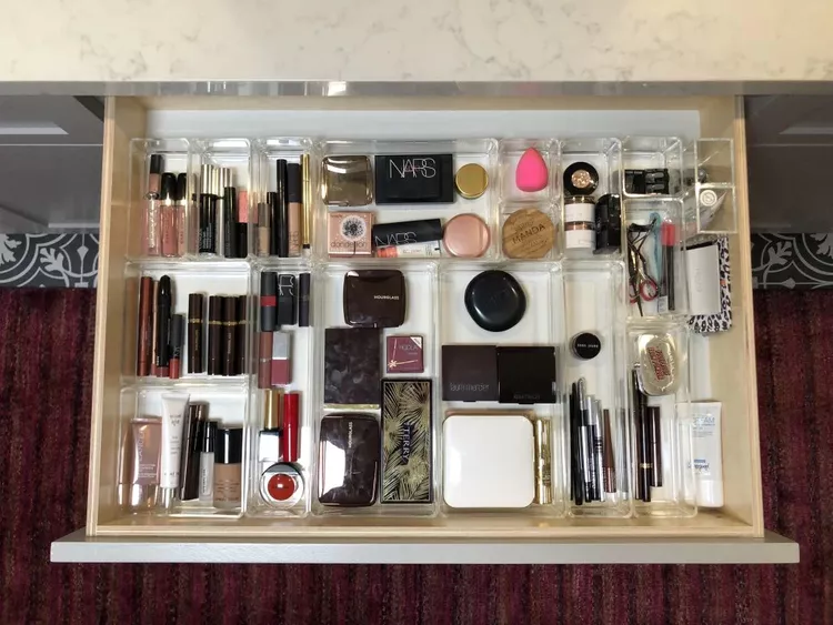 Organized bathroom drawer with clear dividers separating makeup skincare and brushes