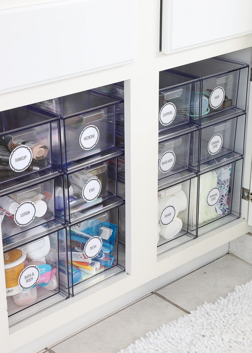 Under bathroom sink cabinet organized with clear labeled storage bins