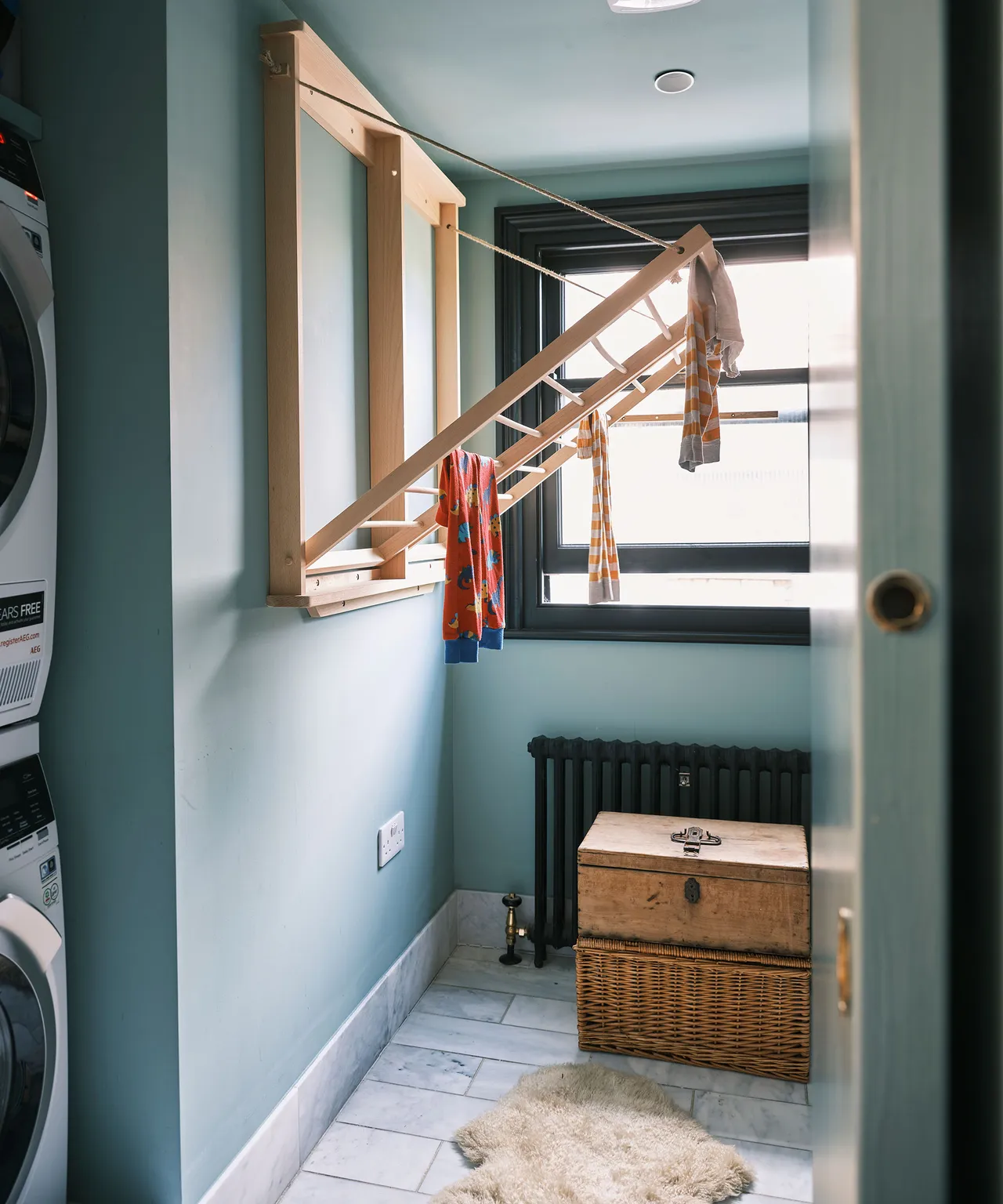 Small laundry room with wall mounted drying rack and neutral styling