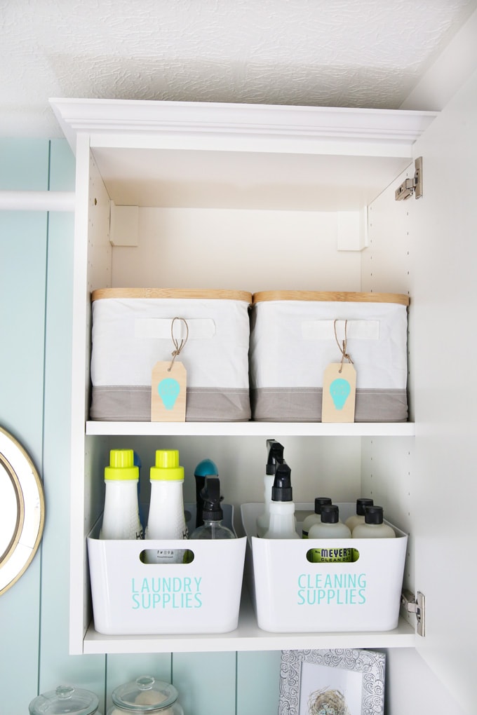 Organized small laundry room with wall shelves and labeled baskets
