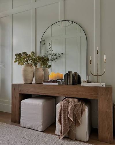 Small entryway with leaning mirror behind console table reflecting light and creating depth